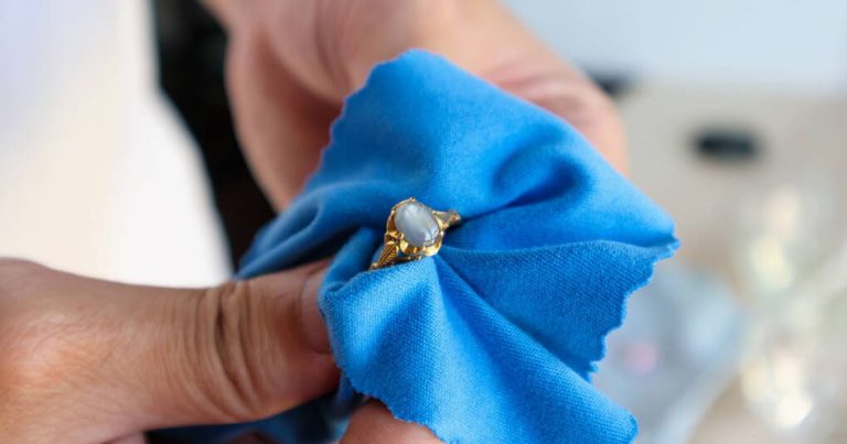 Kék kendővel arany gyűrűt tisztít.
